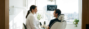 Dentist showing a patient a website on a tablet during an appointment